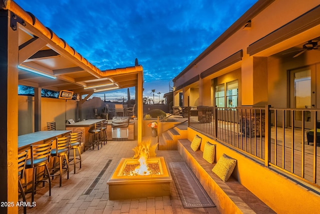 view of patio with outdoor dry bar, fence, and a fire pit