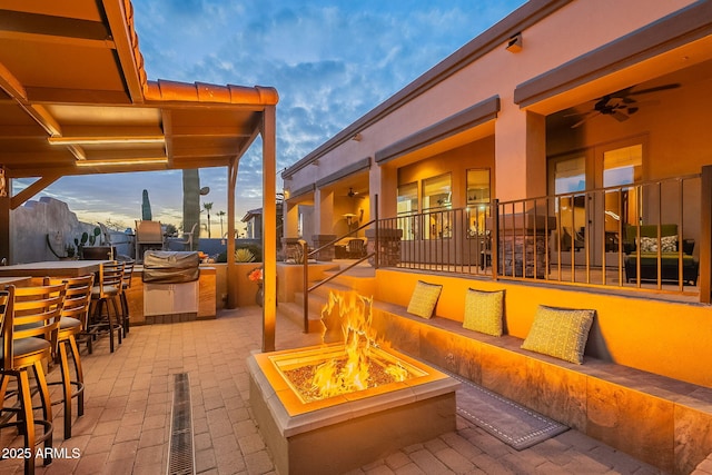 view of patio featuring a fire pit, outdoor dry bar, and a ceiling fan