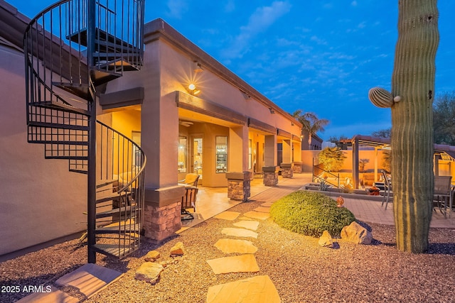 back of house featuring stucco siding, a patio area, and stairs