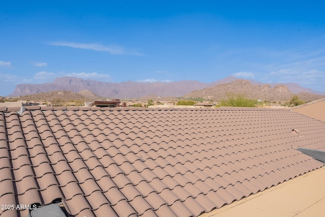 exterior space with a tile roof, a mountain view, and fence