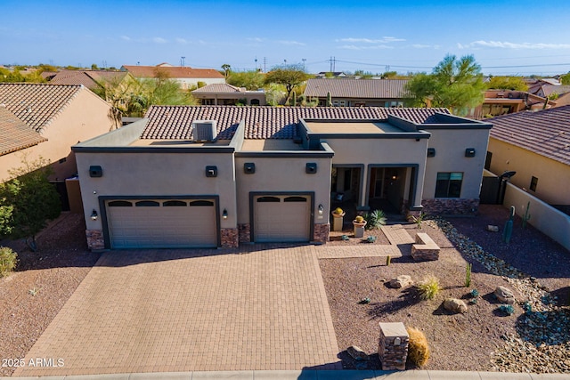 view of front of home with a garage, fence, stone siding, decorative driveway, and stucco siding