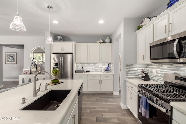 kitchen featuring appliances with stainless steel finishes, a sink, backsplash, pendant lighting, and light countertops
