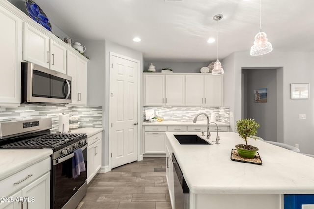 kitchen with appliances with stainless steel finishes, a sink, recessed lighting, decorative backsplash, and an island with sink
