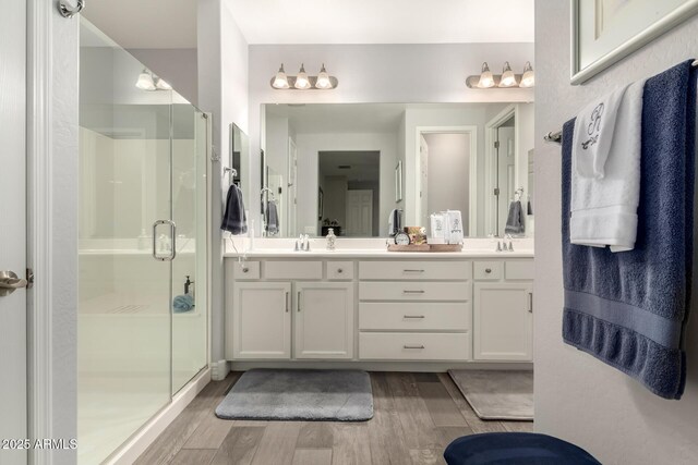 full bath with wood finished floors, double vanity, and a shower stall
