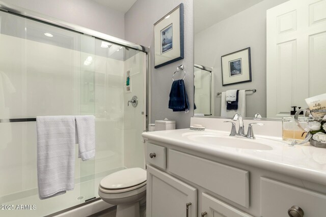 bathroom featuring toilet, a shower stall, and vanity