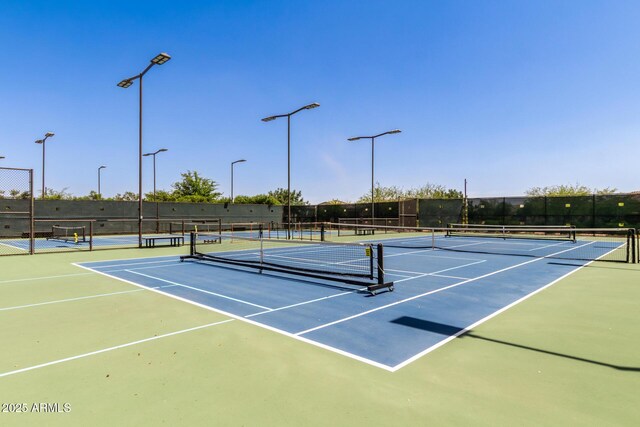 view of tennis court with community basketball court and fence