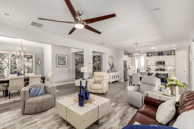 living area with a chandelier, light wood-style flooring, baseboards, ceiling fan, and recessed lighting