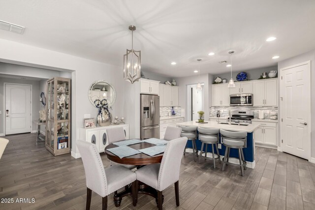 dining space featuring dark wood-style flooring, recessed lighting, and a chandelier