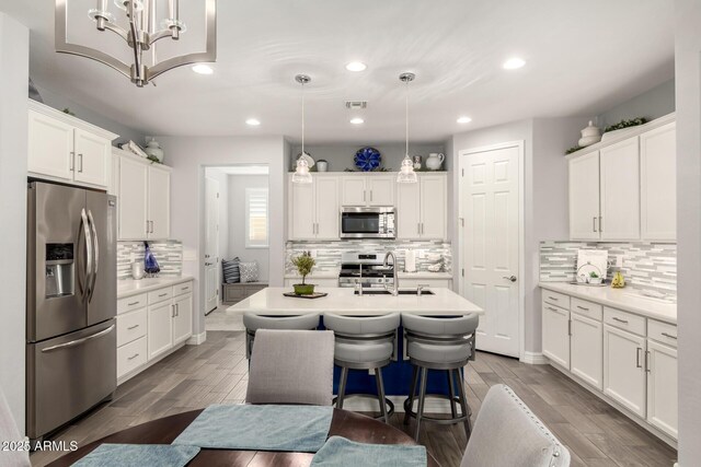 kitchen featuring stainless steel appliances, a sink, tasteful backsplash, recessed lighting, and white cabinets