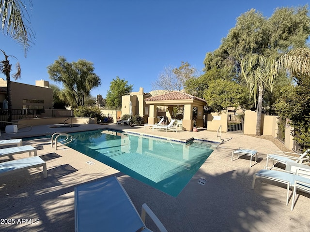 community pool with a patio area, fence, and a gazebo