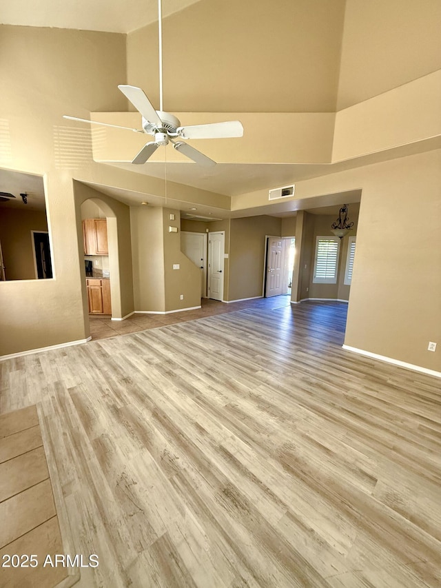 unfurnished living room featuring a ceiling fan, baseboards, visible vents, and light wood finished floors