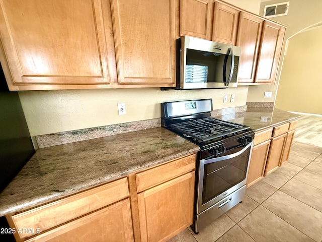 kitchen featuring light tile patterned floors, stainless steel appliances, and visible vents