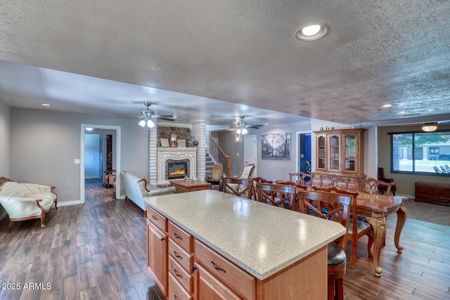 kitchen with baseboards, a fireplace, a textured ceiling, and open floor plan