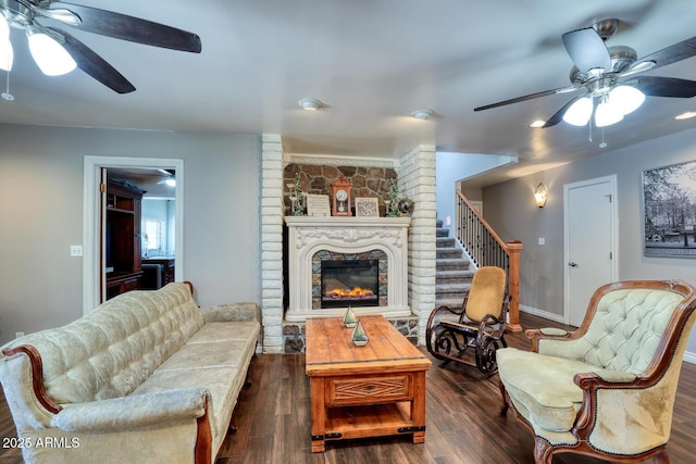 living area featuring baseboards, a fireplace, a ceiling fan, and dark wood-style floors