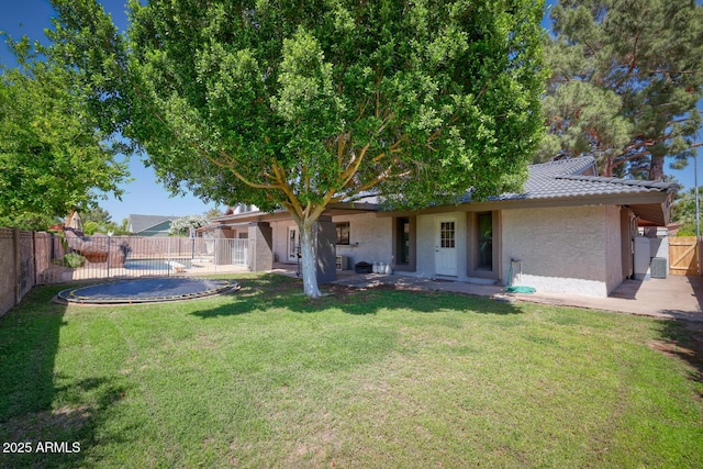 back of house featuring a lawn, a tiled roof, a fenced backyard, and stucco siding