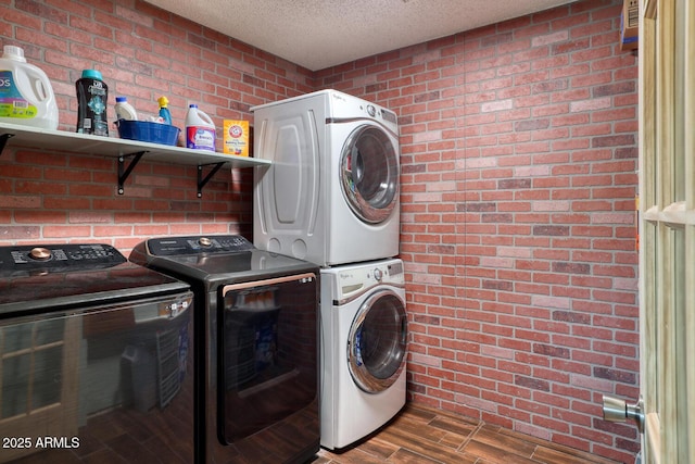 laundry area with a textured ceiling, brick wall, wood finished floors, and laundry area