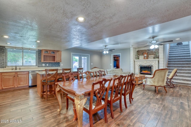 dining area with a textured ceiling, ceiling fan, wood finished floors, and a fireplace