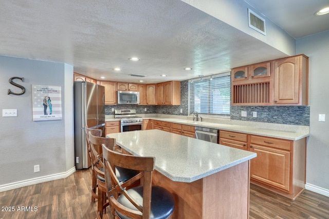 kitchen with stainless steel appliances, baseboards, decorative backsplash, dark wood-type flooring, and visible vents
