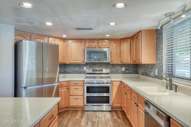 kitchen featuring appliances with stainless steel finishes, a sink, light countertops, dark wood-type flooring, and visible vents