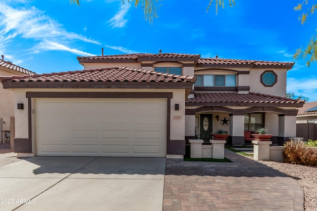 mediterranean / spanish house featuring driveway, an attached garage, and stucco siding