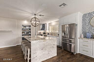 28422 N 32nd Ln, Phoenix, AZ 85083 - kitchen with dark wood-style floors, a center island, an inviting chandelier, white cabinetry, and stainless steel fridge with ice dispenser