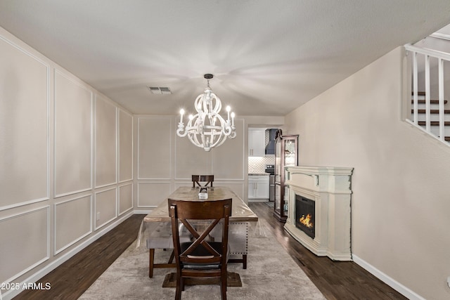 28422 N 32nd Ln, Phoenix, AZ 85083 - dining room featuring visible vents, a glass covered fireplace, dark wood-style flooring, an inviting chandelier, and a decorative wall