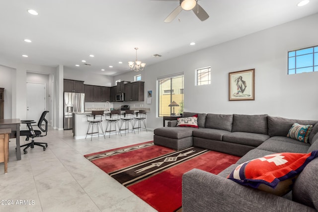 tiled living room with ceiling fan with notable chandelier