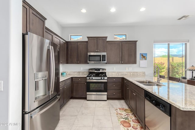 kitchen featuring light stone countertops, recessed lighting, a sink, stainless steel appliances, and dark brown cabinetry