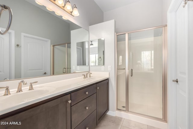 bathroom featuring tile patterned floors, double vanity, a stall shower, and a sink