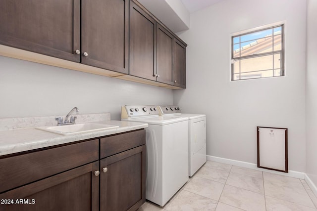 washroom featuring a sink, baseboards, cabinet space, and washer and clothes dryer