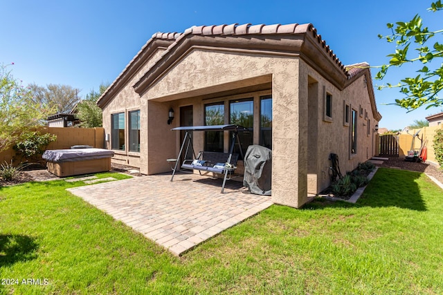 back of house featuring a patio, a yard, a fenced backyard, stucco siding, and a hot tub