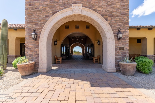 property entrance with stone siding, stucco siding, and a tiled roof
