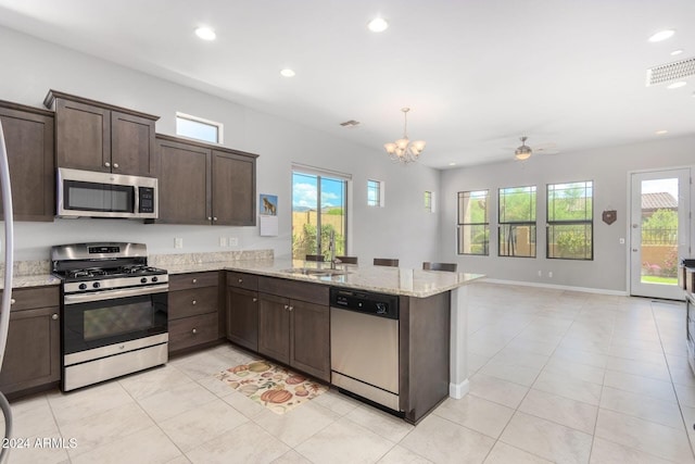 kitchen featuring visible vents, a sink, stainless steel appliances, dark brown cabinetry, and a peninsula
