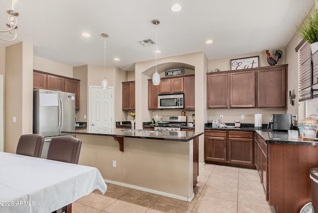 2748 E Dennisport Ave, Gilbert, AZ 85295 - kitchen with appliances with stainless steel finishes, light tile patterned floors, hanging light fixtures, a kitchen bar, and dark stone counters