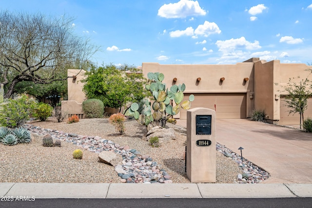 adobe home featuring driveway, an attached garage, and stucco siding