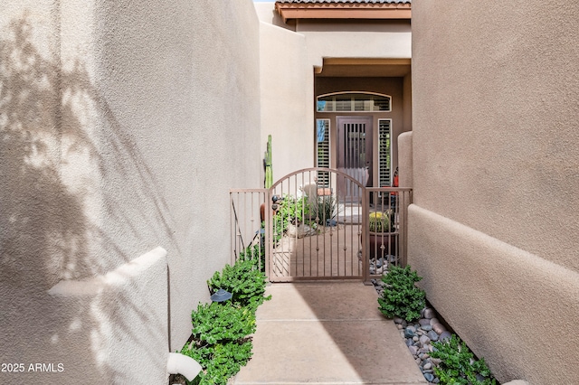 entrance to property with a gate, a tile roof, and stucco siding