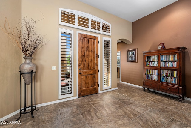 foyer featuring arched walkways and baseboards