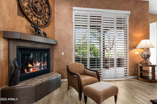 living area with baseboards, a tiled fireplace, and wood finished floors