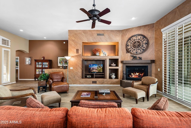 living room featuring a large fireplace, arched walkways, wood finished floors, and recessed lighting