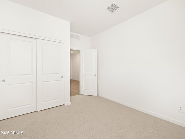 unfurnished bedroom featuring light carpet and a closet