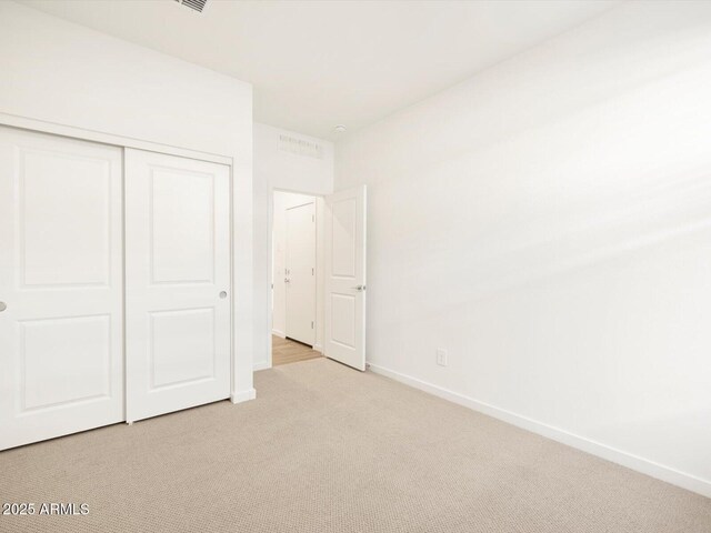 unfurnished bedroom with light carpet and a closet