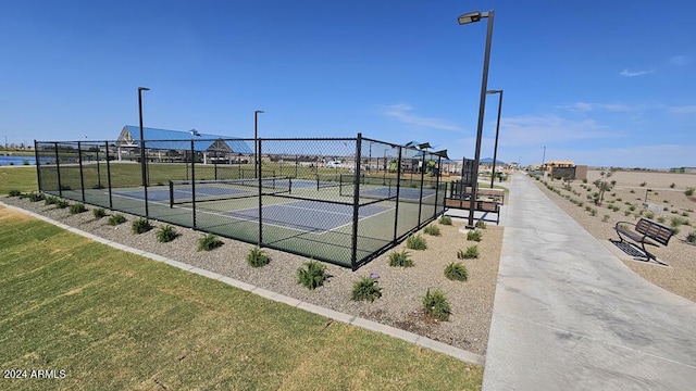 view of sport court featuring a water view and a lawn