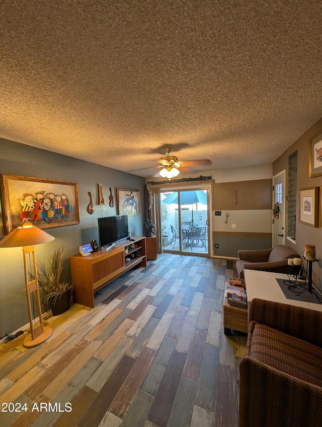 living room featuring ceiling fan, wood-type flooring, and a textured ceiling