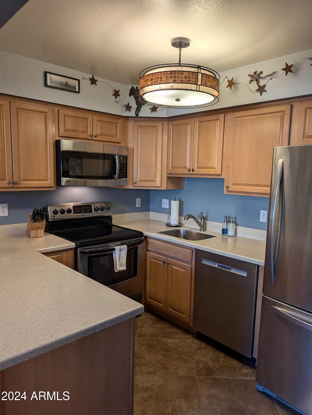 kitchen with light stone countertops, a textured ceiling, stainless steel appliances, sink, and decorative light fixtures