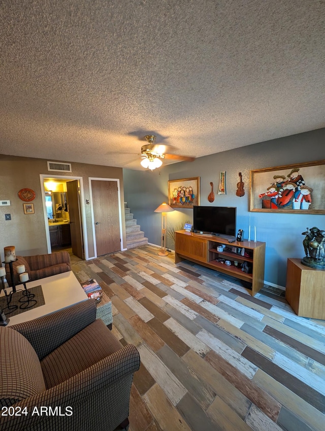 living room with ceiling fan, wood-type flooring, and a textured ceiling