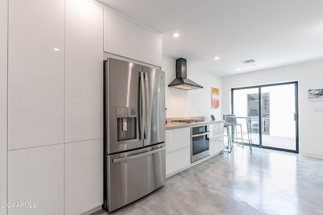 kitchen with appliances with stainless steel finishes, wall chimney exhaust hood, and white cabinets