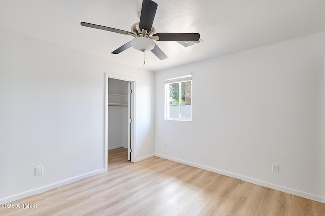 751 E Southern Ave, Phoenix, AZ 85040 - unfurnished bedroom with light wood-style flooring, a closet, a ceiling fan, a walk in closet, and baseboards