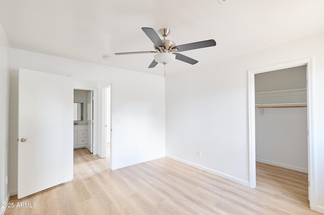 751 E Southern Ave, Phoenix, AZ 85040 - unfurnished bedroom with a closet, baseboards, light wood-type flooring, a ceiling fan, and a walk in closet
