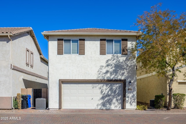 view of front of house with central AC unit, stucco siding, a tile roof, and decorative driveway