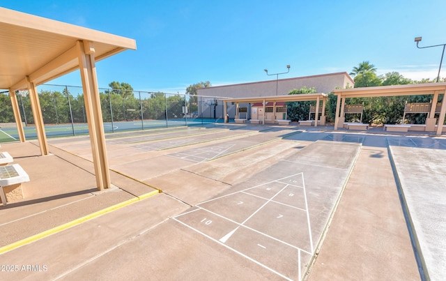 view of property's community featuring shuffleboard and fence